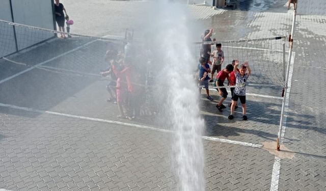 Hatay'da konteyner kentteki öğrenciler itfaiyenin sıktığı suyla serinledi